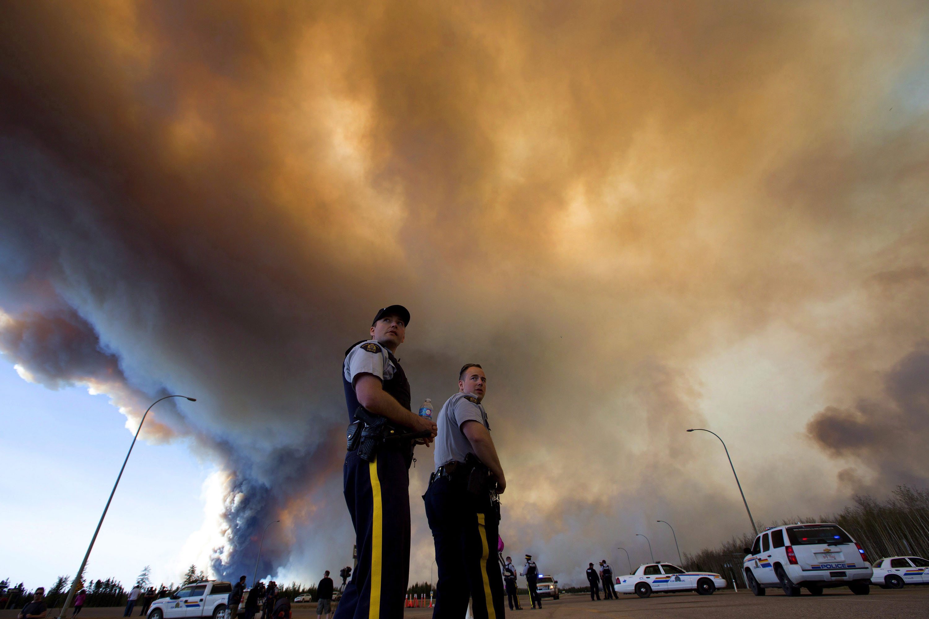 Police officers direct traffic under a cloud of smoke from a wildfire in Fort McMurray, Alberta.