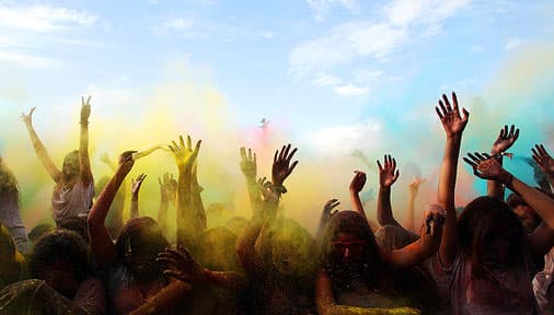 hands waving through colour clouds in a concert audience