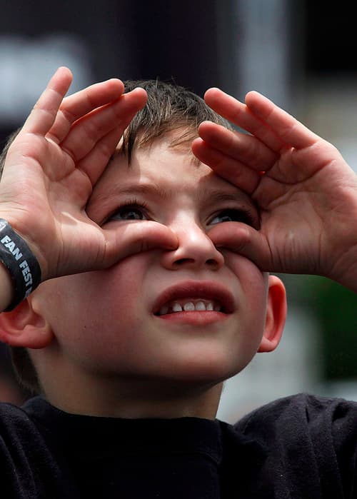 custom content - A boy looking up and shielding his eyes from the sun.