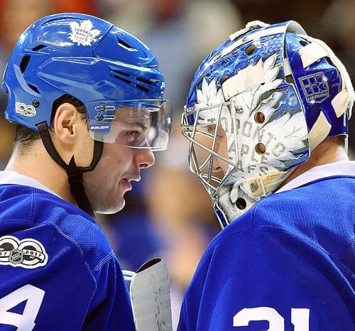 Toronto Maple Leafs teammates talking to each other on the ice.