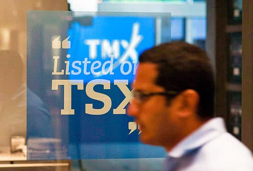 financial trader in front of a sign that says "listed on T S X"