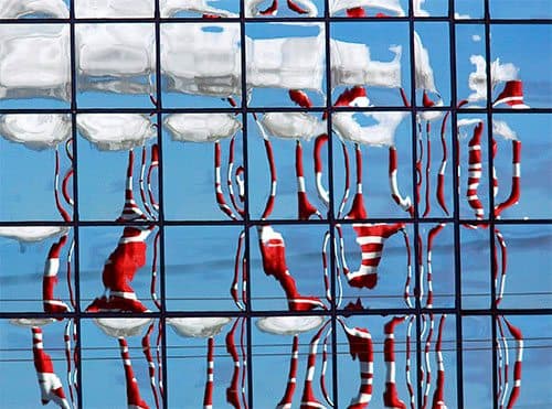 Smoke stacks reflected on office building windows.