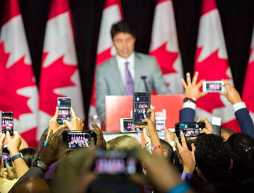 Audience members take a pictures with smartphones as Prime Minister Justin Trudeau speaks at an event at Paramount Fine Foods in Mississauga.