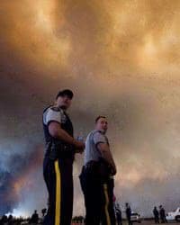 Police officers direct traffic under a cloud of smoke from a wildfire in Fort McMurray.