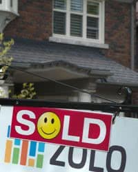 Real Estate sign saying "Sold Out" in front of a house.