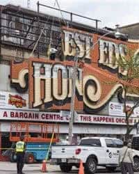 Workers remove part of the iconic sign from the shuttered Honest Eds department store in Toronto.