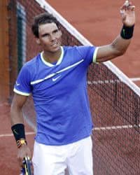 Male tennis player waving to the crowd as he walks off the court.