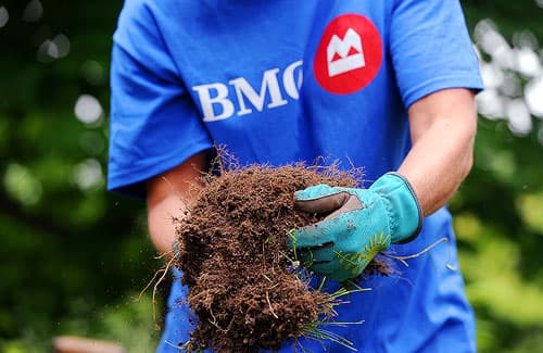 Bank of Montreal employee wear corporate t-shirt holding dirt in gloved hands
