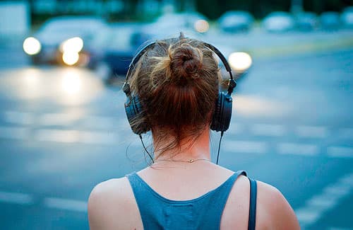 Picture of a woman from behind wearing large headphones.