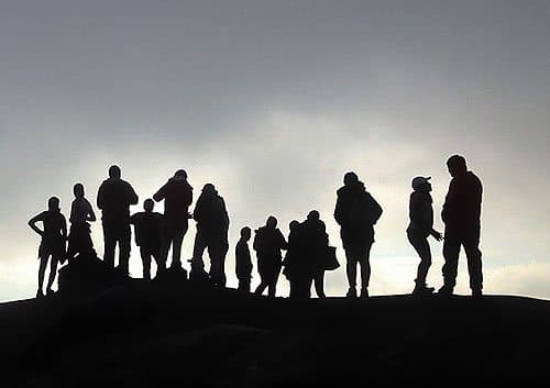 Silhouette of a group of people standing on a hill.