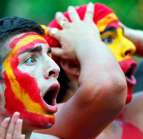 Spain soccer fans with painted faces reacting to a World Cup match.