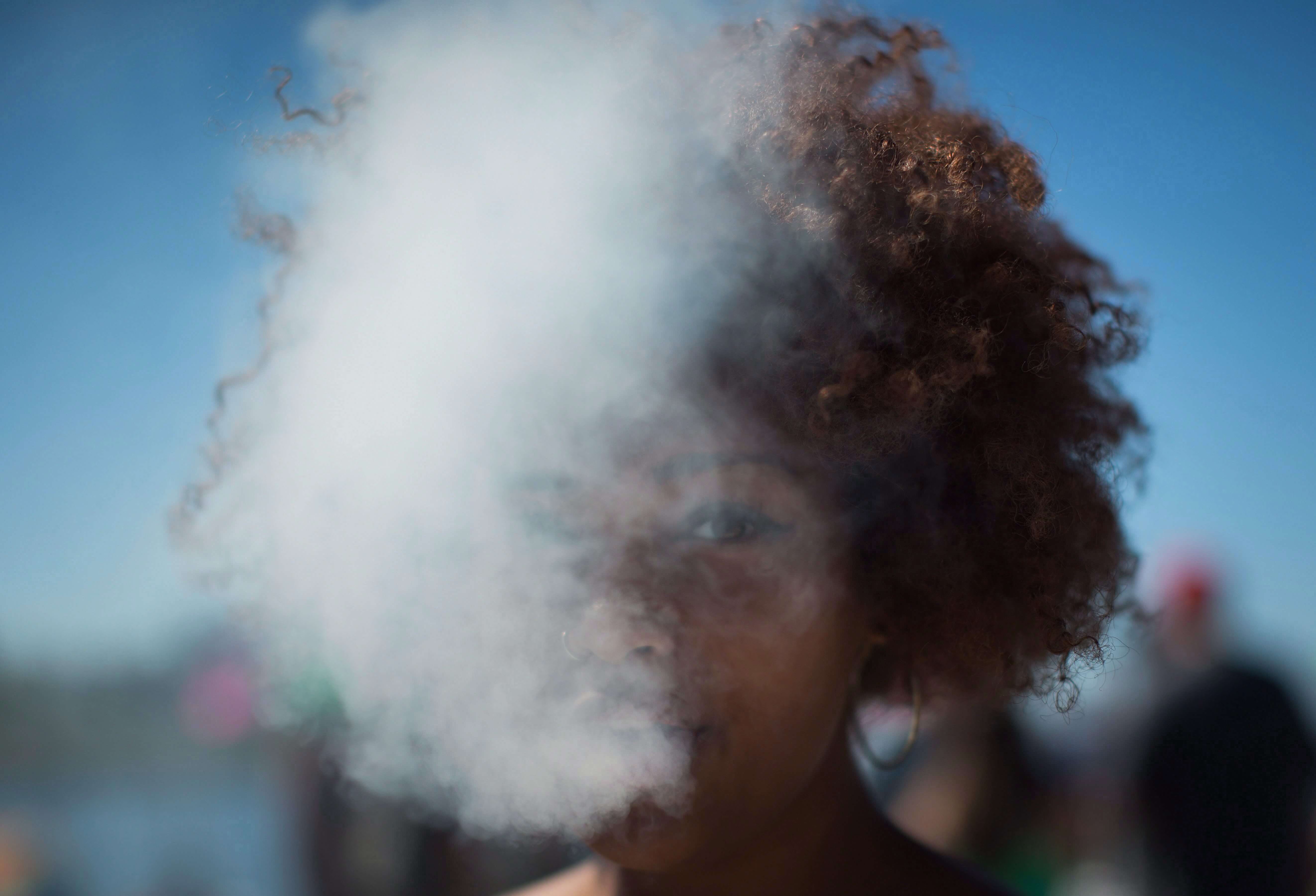 A woman exhales smoke after taking a hit from a bong.