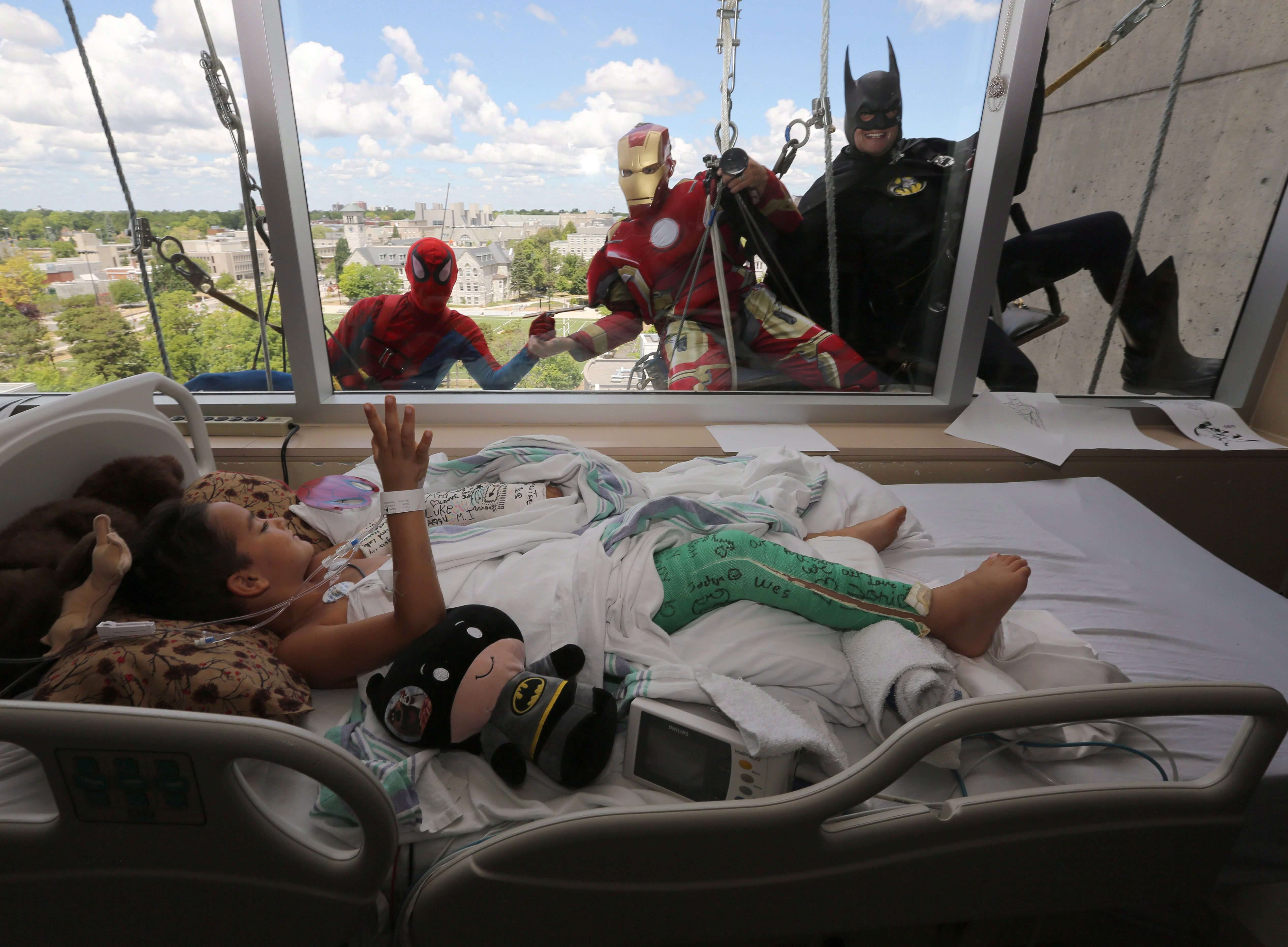 Seven-year-old Luke Carter waves to window washers dressed as Spiderman, Ironman and Batman at Kingston General Hospital in Kingston, Ontario.