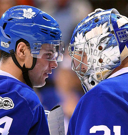 Toronto Maple Leafs teammates talking to each other on the ice.