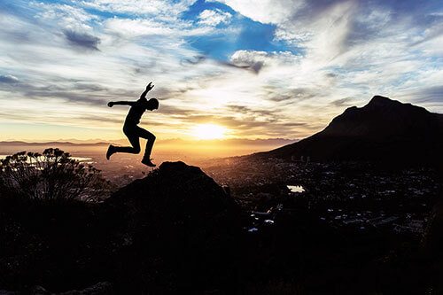 Silhouette of a person leaping through the air during sunset.