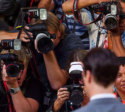 Photographers taking pictures of a man at a podium.