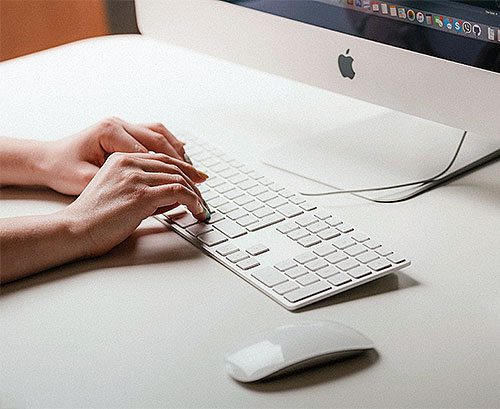 Hands typing on a computer keyboard.