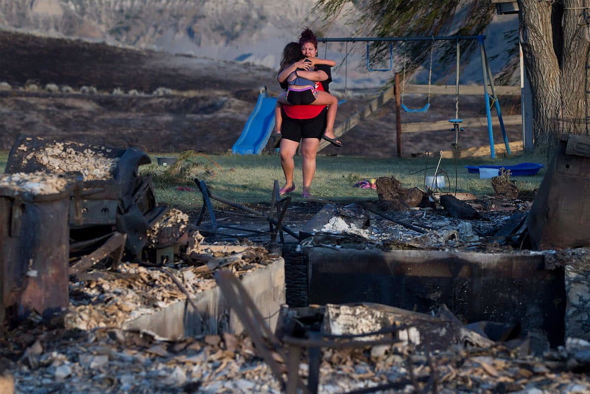 Kelsey Thorne holds her daughter Nevaeh Porter, 8, as they both cry while viewing the remains of their home where they lived with her parents that was destroyed by wildfire on the Ashcroft First Nation, near Ashcroft, B.C., late Sunday July 9, 2017