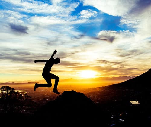 Silhouette of a person leaping through the air during sunset.