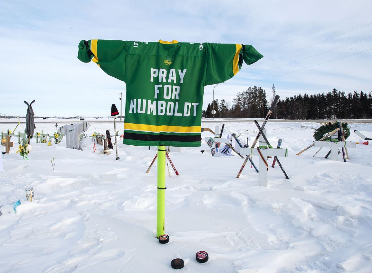 A hockey jersey reading "Pray for Humboldt" raised above the winter landscape near the sight of the crash.