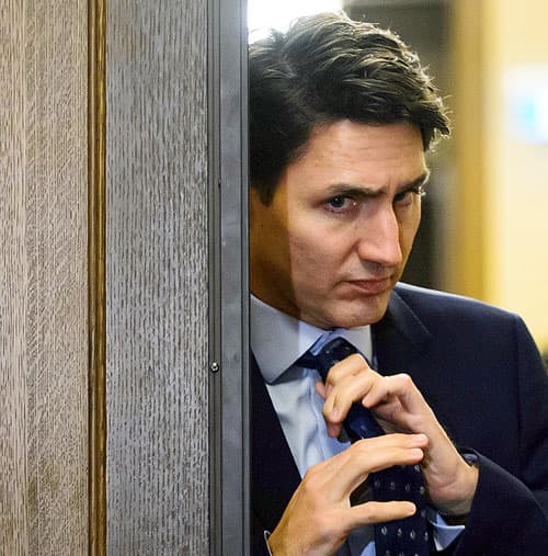 Prime Minister Justin Trudeau adjusts his tie as he leaves a cabinet meeting