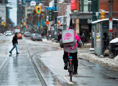 A foodora delivery driver navigates the streets of Toronto in winter