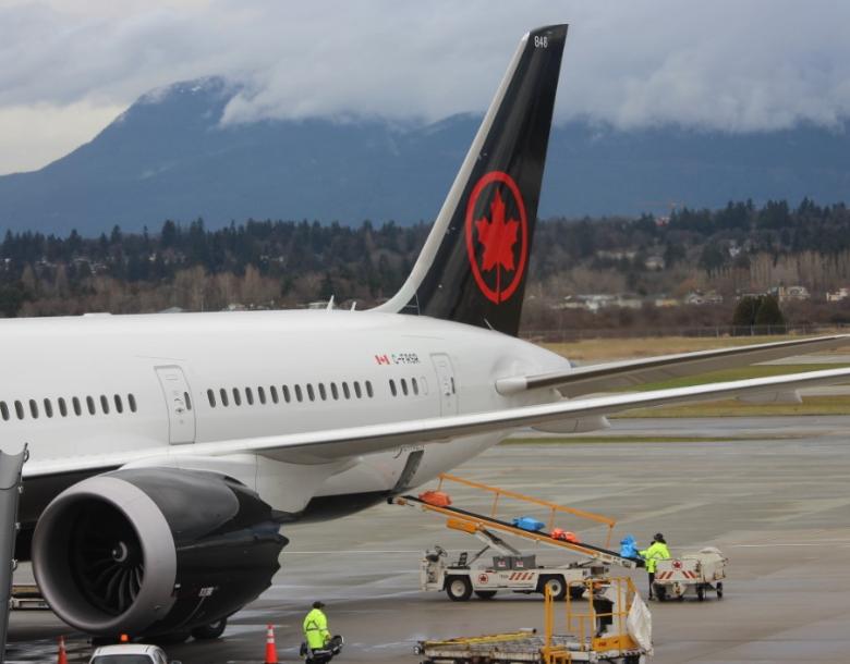Suitcases are unloaded from the back of an Air Canada plane