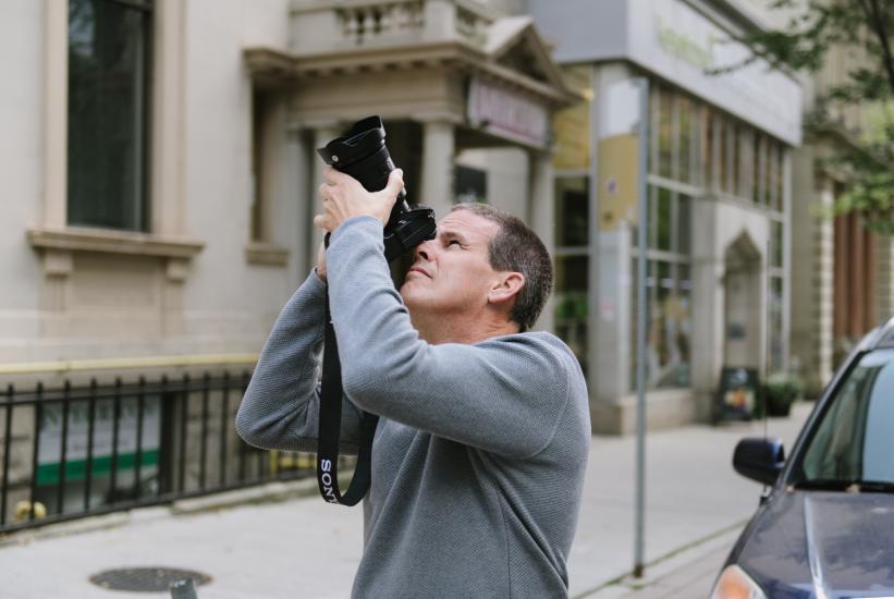 A male photographer points his sony camera up to the sky while shooting